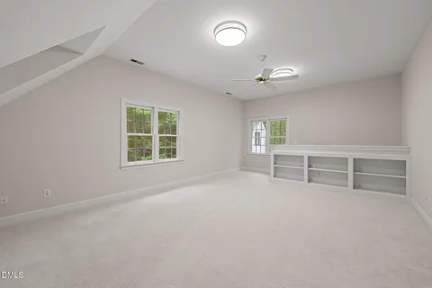 an empty room with windows and fan