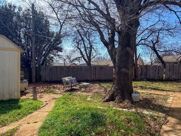 a backyard of a house with barbeque oven and a tree
