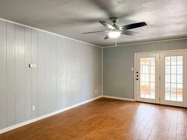 an empty room with wooden floor fan and windows