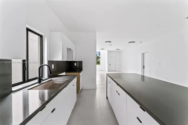 a large kitchen with kitchen island granite countertop a sink and refrigerator