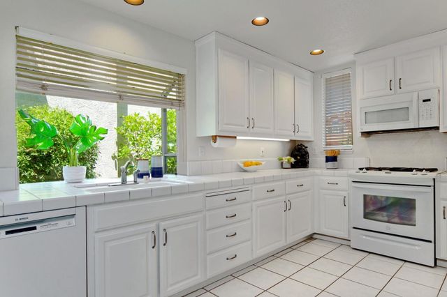 a kitchen with white cabinets and a window