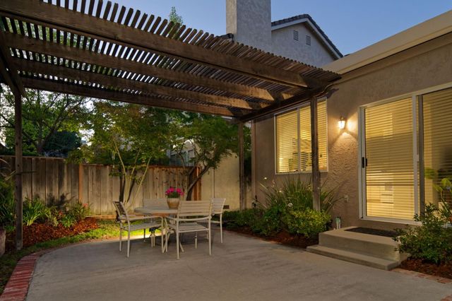 a view of a chairs and table in the patio next to a yard