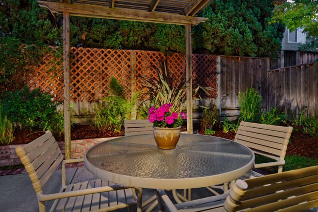 a view of a patio with table and chairs potted plants and a wooden fence