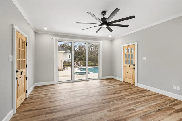 a view of an empty room with a window and wooden floor