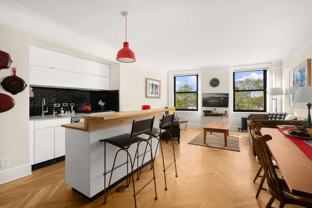 a kitchen with stainless steel appliances granite countertop a stove a sink a dining table and chairs with wooden floor