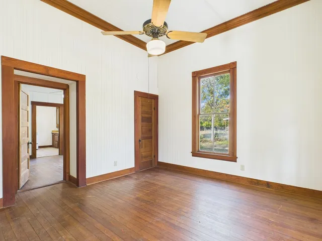 a view of an empty room with a window and wooden floor