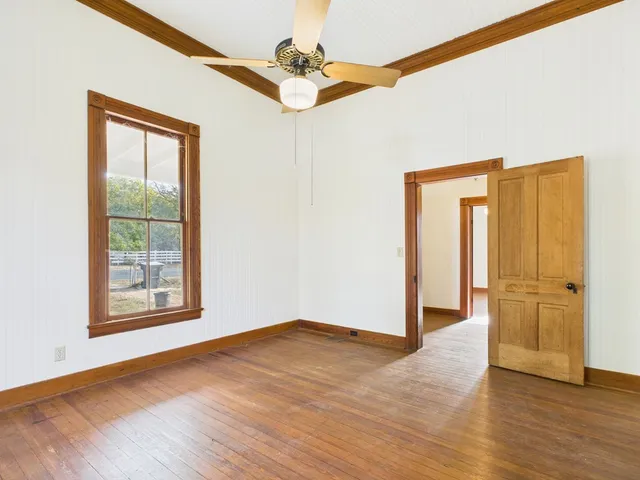 an empty room with wooden floor cabinet and windows
