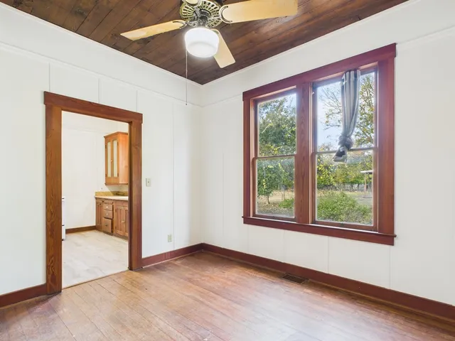 a view of an empty room with a window and wooden floor