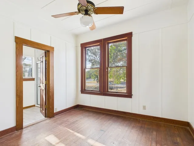 a view of an empty room with a window and wooden floor