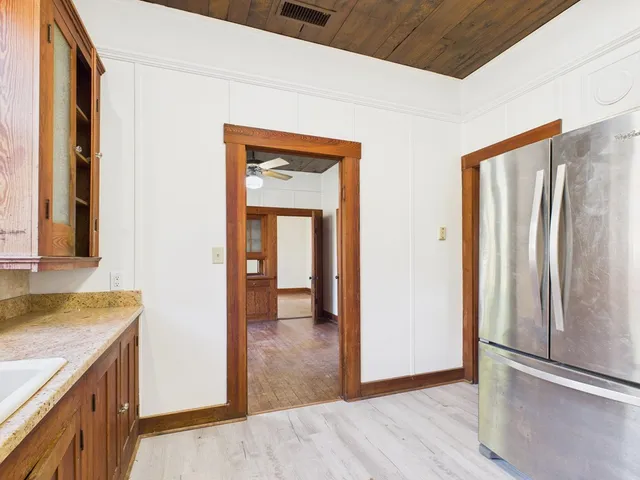 a view of a hallway with wooden floor and a kitchen