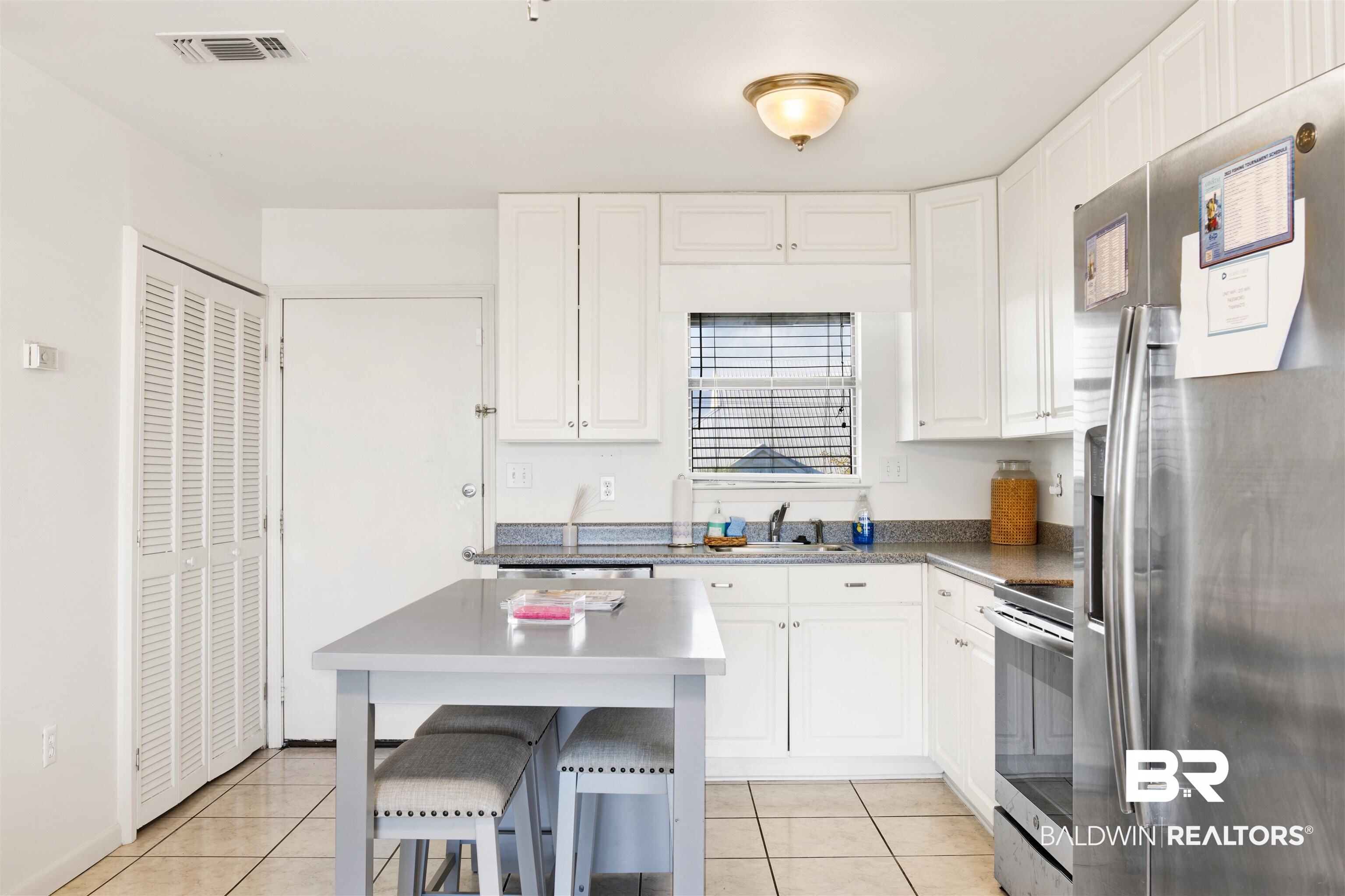 26913 Marina Road, Unit 213 Orange Beach, AL 36561 - Photo 8 of 30 Kitchen with light tile patterned floors, appliances with stainless steel finishes, white cabinetry, sink, and a kitchen island