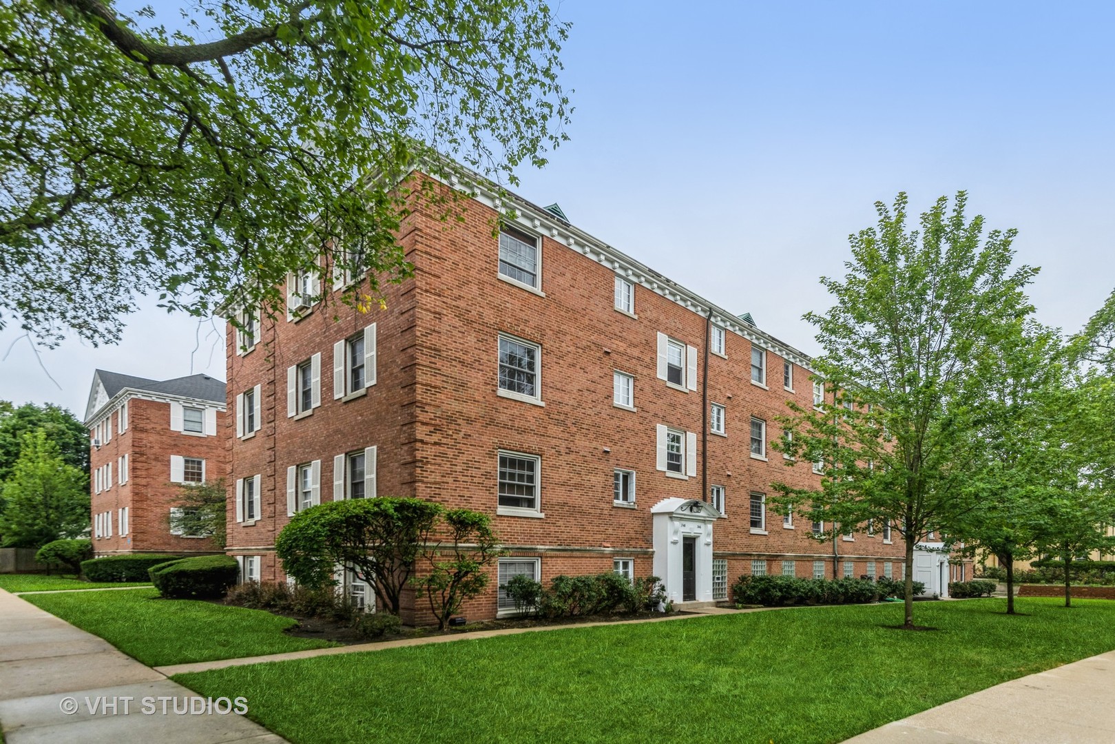 a view of a building next to a yard with big trees