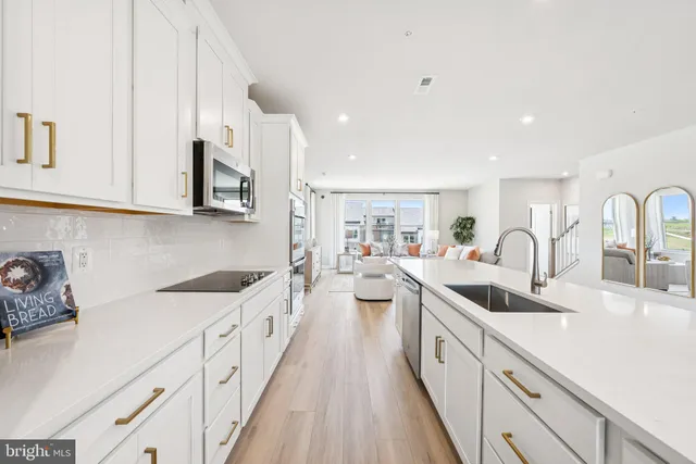 a large white kitchen with stainless steel appliances granite countertop lots of white cabinets a sink and dishwasher