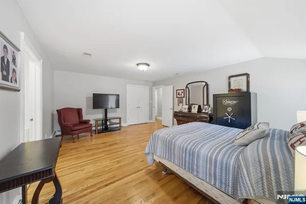 a spacious bedroom with a bed and dresser with wooden floor