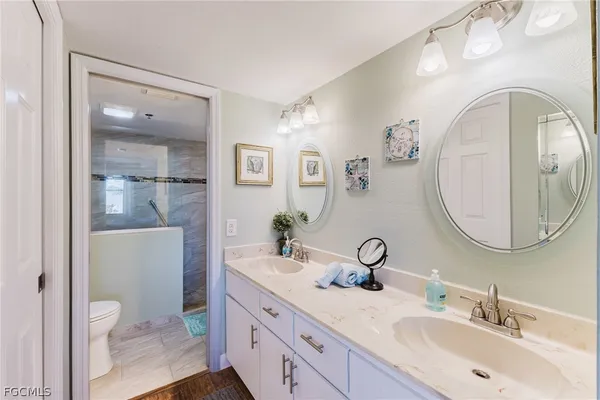 a bathroom with a granite countertop toilet a sink and mirror