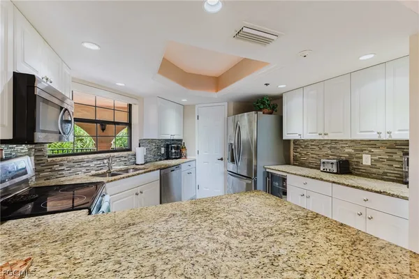 a kitchen with stainless steel appliances kitchen island granite countertop a stove a sink and a refrigerator