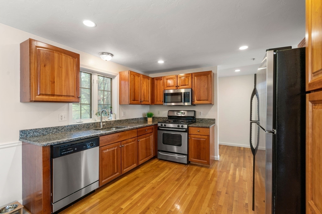 995 Trapelo Road, Unit 1 Waltham, MA 02452 - Photo 6 of 19 a kitchen with stainless steel appliances granite countertop a refrigerator a sink dishwasher a stove and white countertops with wooden floor