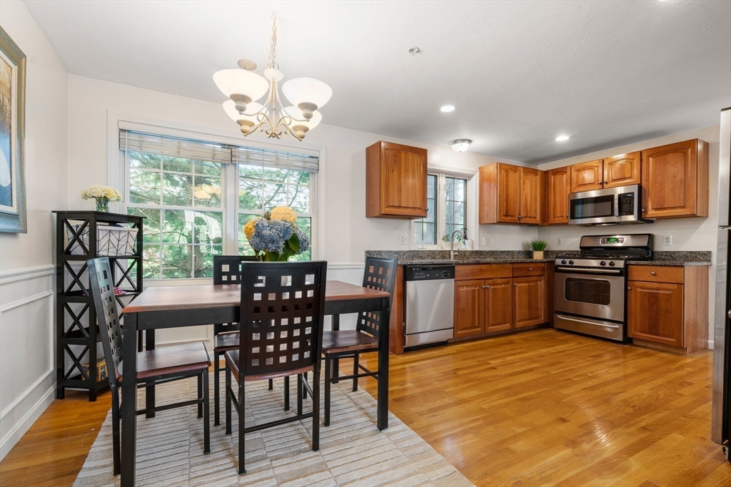 995 Trapelo Road, Unit 1 Waltham, MA 02452 - Photo 7 of 19 a kitchen with stainless steel appliances granite countertop a stove top oven a sink dishwasher a dining table and chairs with wooden floor