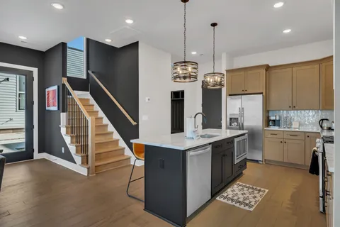 a kitchen with stainless steel appliances kitchen island granite countertop a refrigerator a oven a sink and island with wooden floor