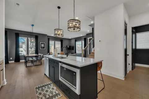 a kitchen with a stove a refrigerator and chairs