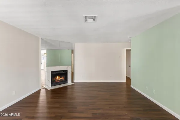 a view of an empty room with wooden floor and a fireplace