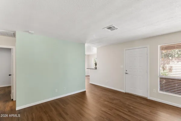 a view of an empty room with wooden floor and a window