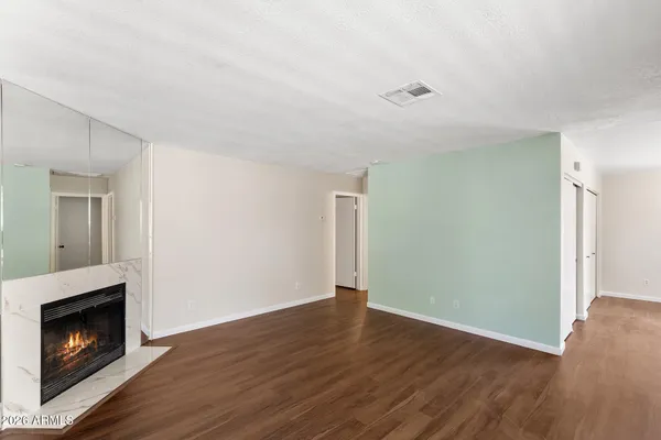 a view of an empty room with wooden floor fireplace and a window