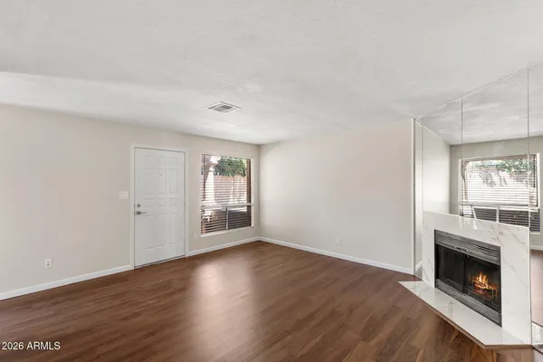 a view of an empty room with wooden floor fireplace and a window