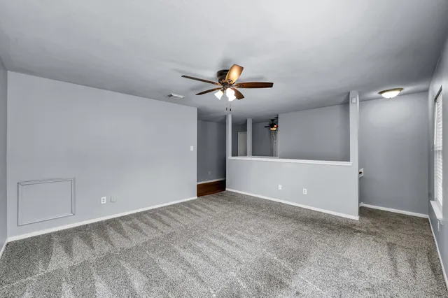 a view of an empty room and cabinet with a ceiling fan