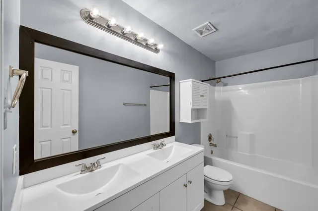a bathroom with a double vanity sink mirror toilet and bathtub