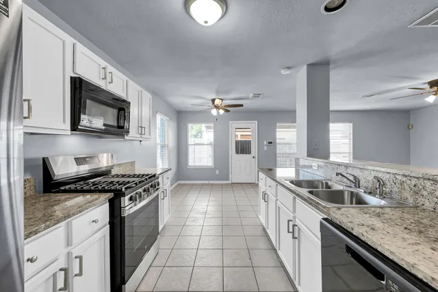 a kitchen with granite countertop stainless steel appliances a sink stove top oven and cabinets