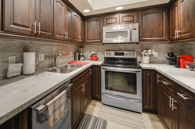 a kitchen with stainless steel appliances granite countertop a stove a sink and a microwave