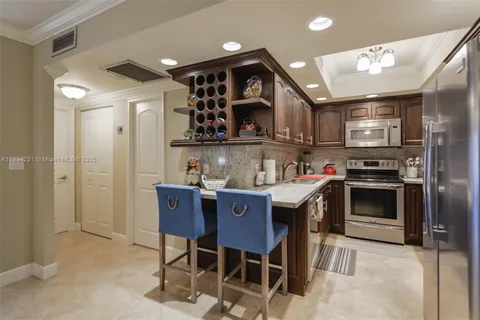 a kitchen with stainless steel appliances granite countertop a stove a sink a refrigerator and chairs