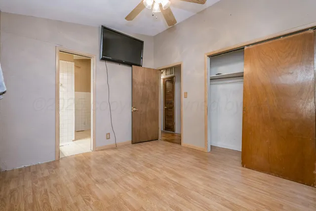 a view of empty room with wooden floor and fan
