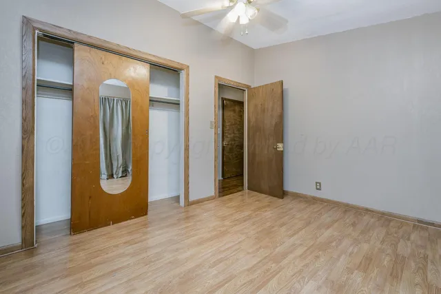 a view of an empty room with wooden floor and closet