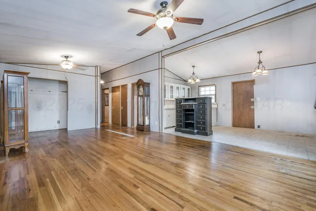 a view of a livingroom with wooden floor a ceiling fan and windows