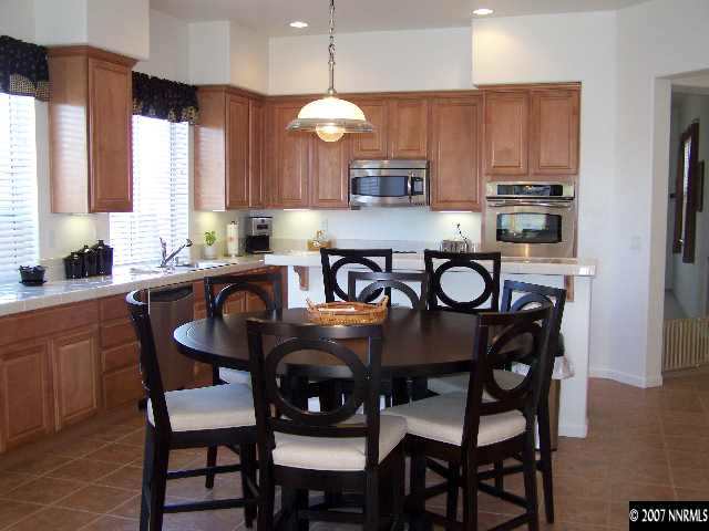 880 Sienna Reno, NV 89512 - Photo 3 of 9 a kitchen with granite countertop a dining table chairs and a refrigerator