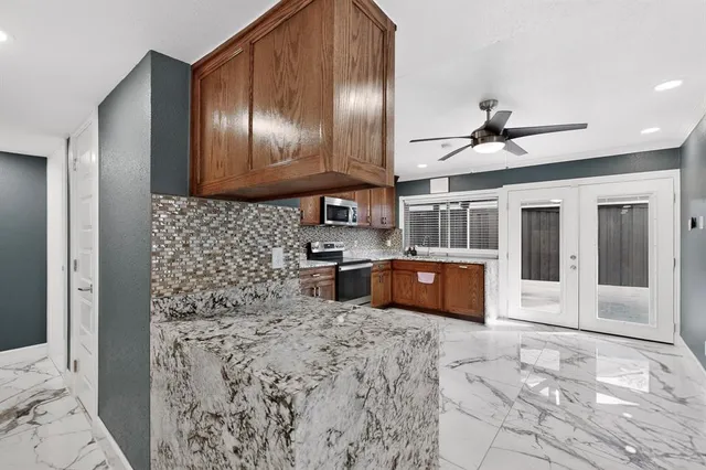a kitchen with stainless steel appliances kitchen island granite countertop a refrigerator and a sink
