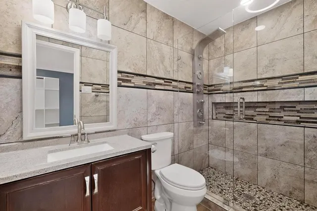 a bathroom with a granite countertop sink a toilet and shower