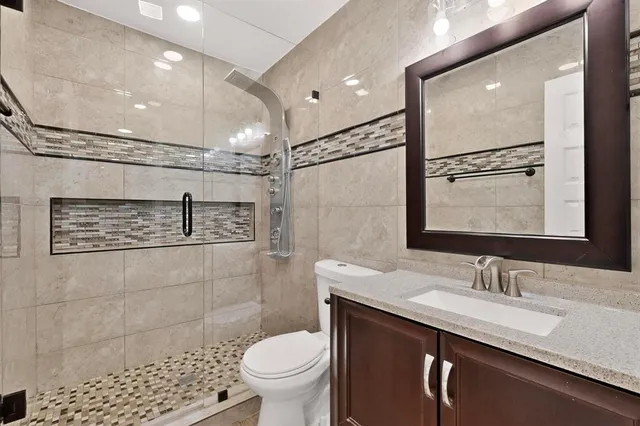 a bathroom with a granite countertop sink toilet and shower