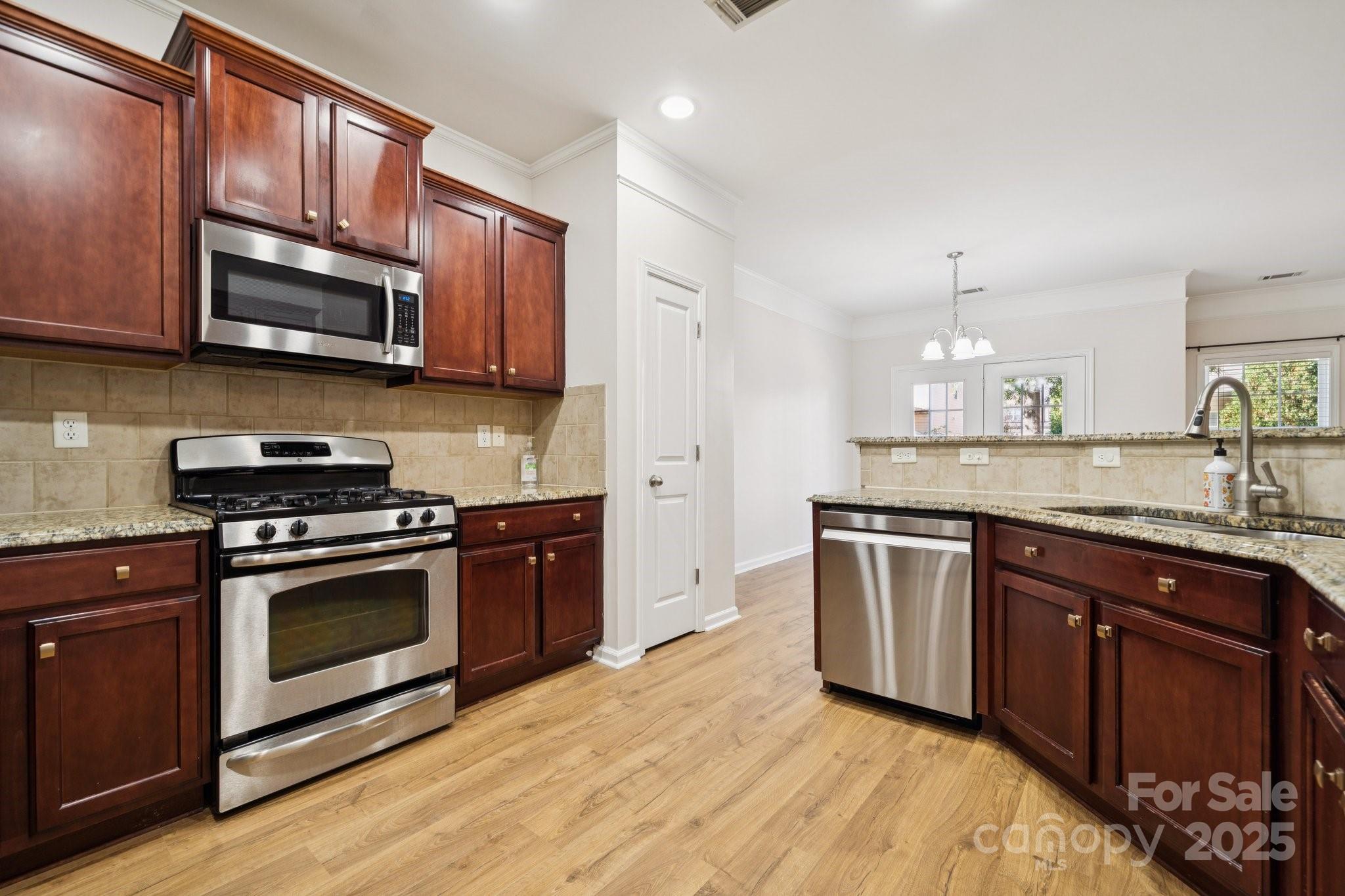 2015 Terrapin Street Indian Trail, NC 28079 - Photo 14 of 31 a kitchen with stainless steel appliances granite countertop a stove a sink dishwasher and a microwave oven with wooden cabinets