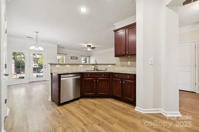 a kitchen with stainless steel appliances granite countertop a sink a stove and a wooden floors