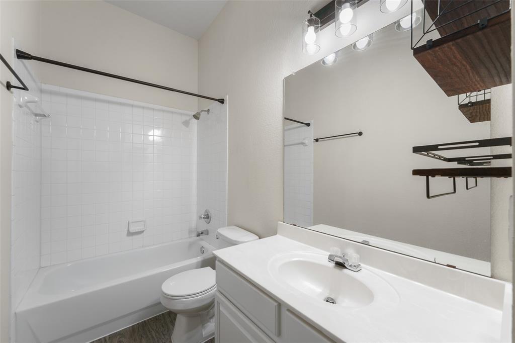 2124 Hickory Ridge Drive Mesquite, TX 75181 - Photo 12 of 16 a bathroom with a sink a toilet a mirror a vanity and shower