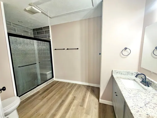 a bathroom with a granite countertop sink toilet and shower