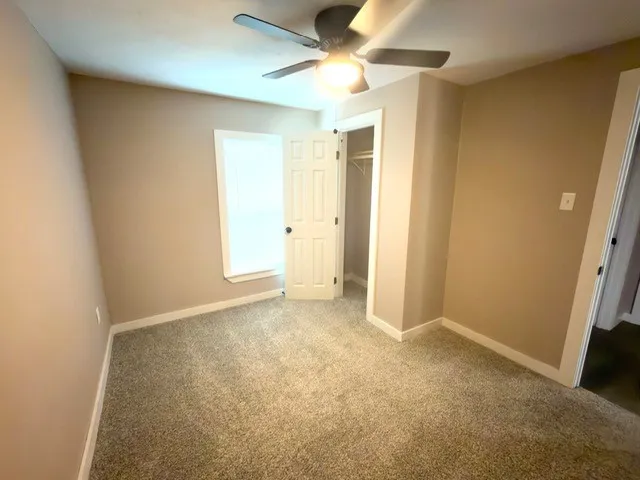 an empty room with a ceiling fan and a window
