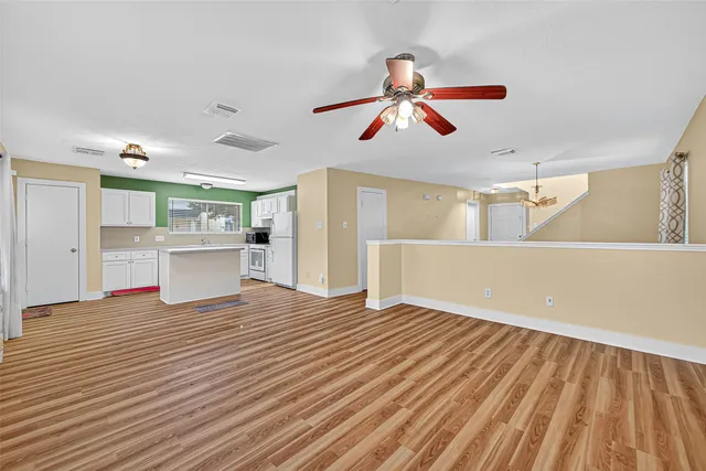a view of a room with wooden floor ceiling fan and window