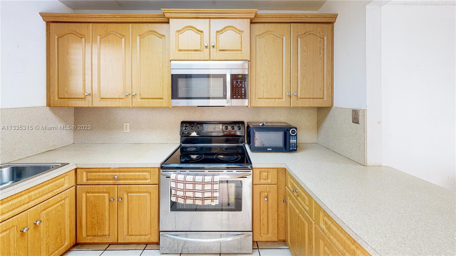1750 West 46th Street, Unit 312 Hialeah, FL 33012 - Photo 3 of 41 a kitchen with a stove a microwave and cabinets