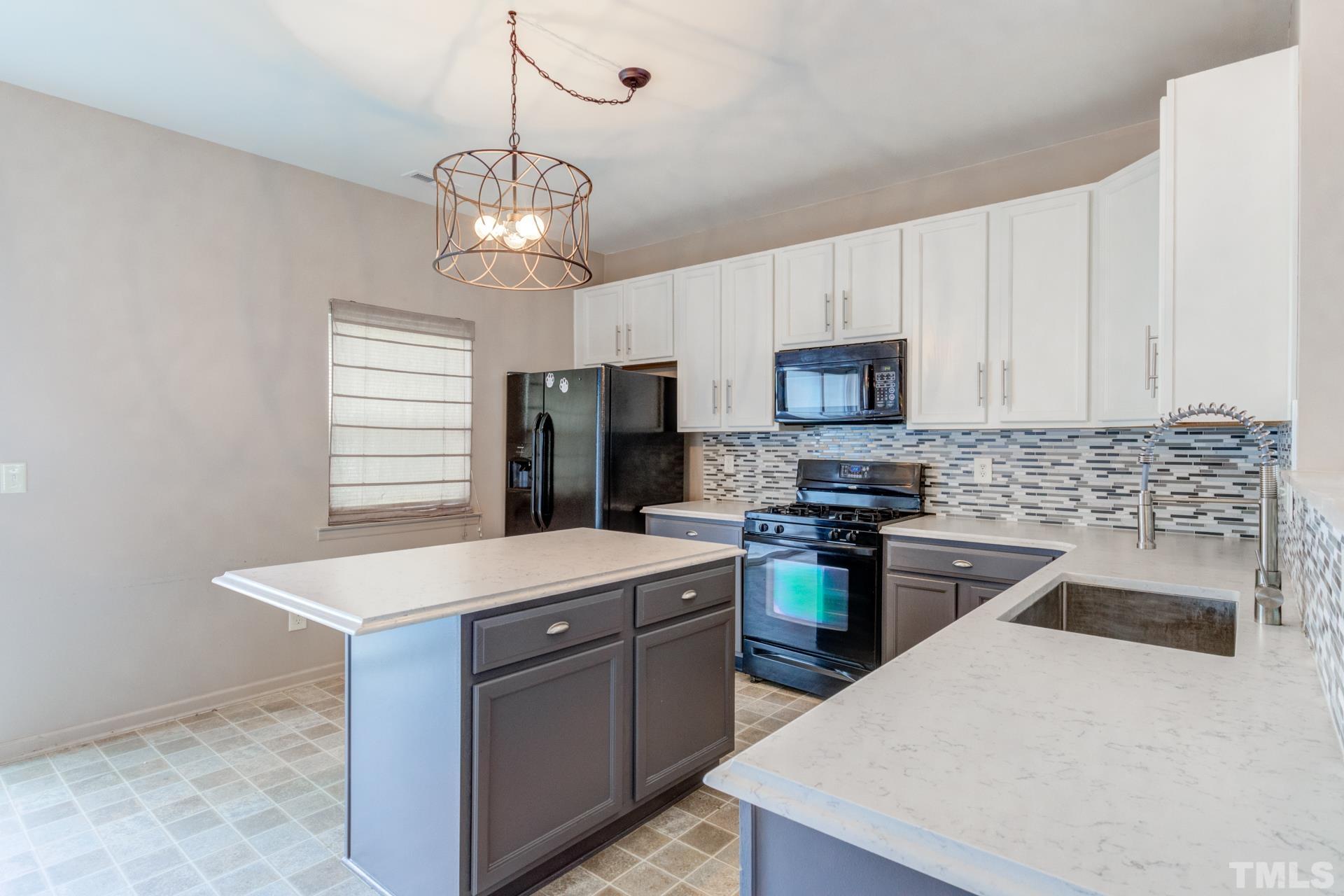 4911 Midstone Lane Raleigh, NC 27610 - Photo 7 of 28 a kitchen with a stove a sink and a refrigerator