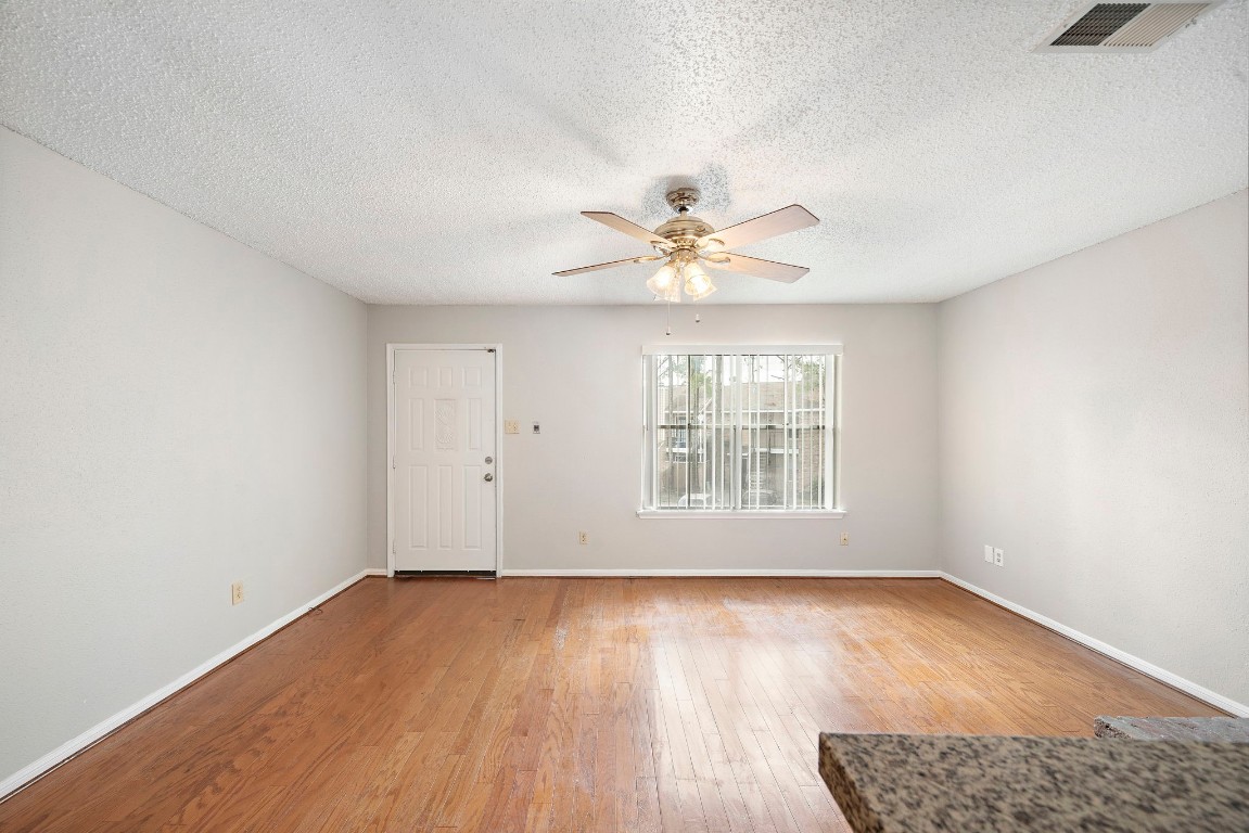 7402 Alabonson Road, Unit 506 Houston, TX 77088 - Photo 3 of 10 an empty room with wooden floor and windows