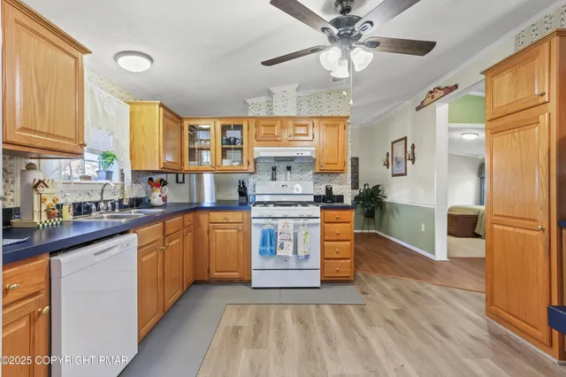 a kitchen with stainless steel appliances a stove a sink dishwasher a refrigerator and a dining table with wooden floor